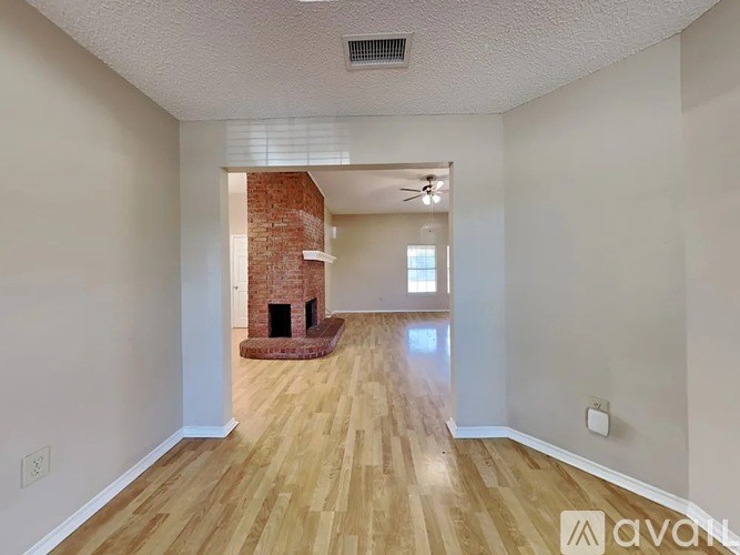 A room with wooden floors and a brick fireplace.
