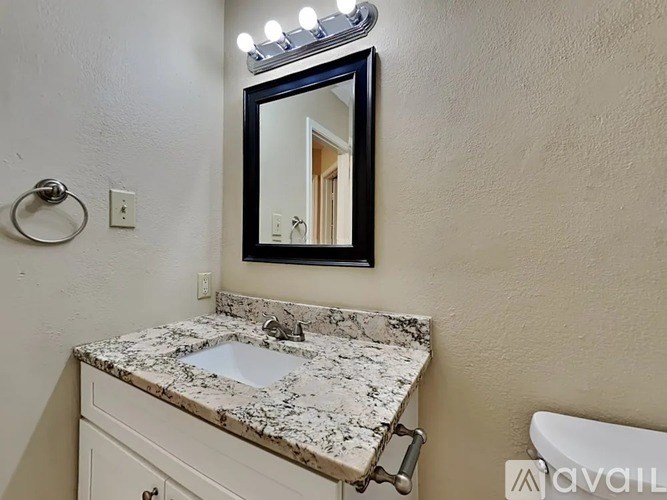 A bathroom with a granite countertop and a mirror above it.