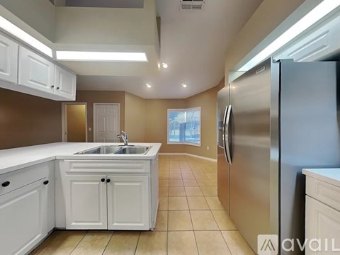 A kitchen with white cabinets and a stainless steel refrigerator.