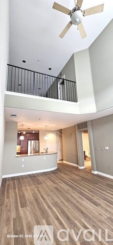 A spacious living room with wood flooring and a ceiling fan.