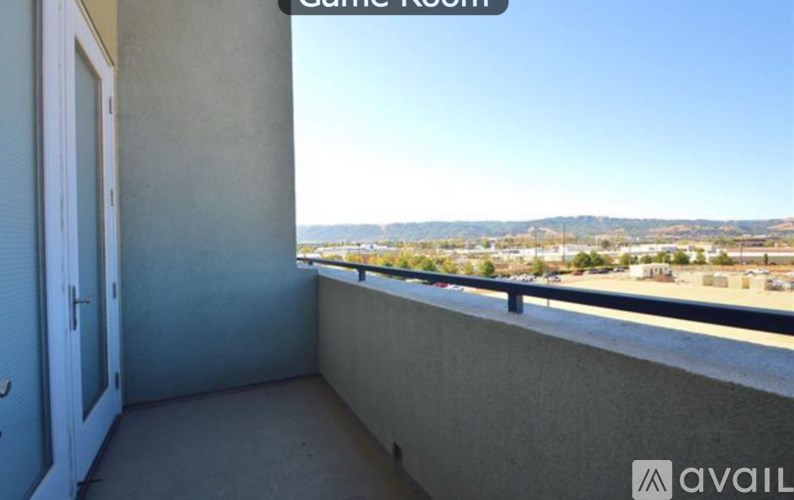 A balcony with a view of the mountains and a parking lot.