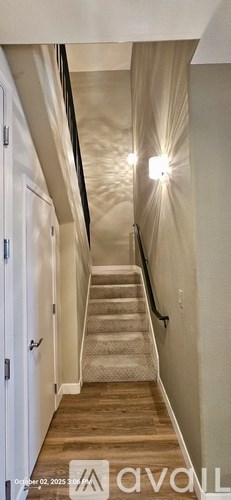 A long hallway with a staircase and a light on the wall.