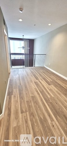 A room with wooden flooring and a balcony with a railing.