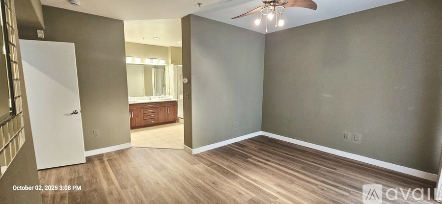 A room with a ceiling fan and a door leading to another room.