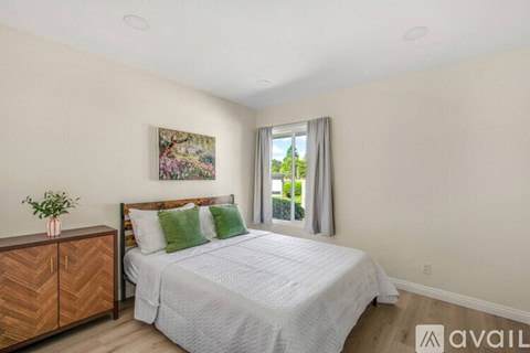 A bedroom with a large bed and a wooden cabinet.