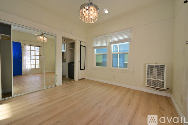 A room with wooden floors and white walls, with a sliding glass door and a window.
