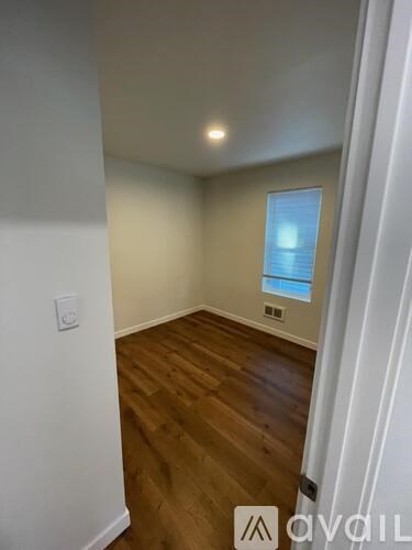 A room with wooden floors and a window with blinds.