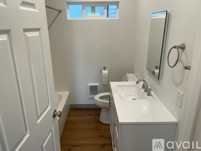 A small bathroom with a toilet, sink, and mirror.