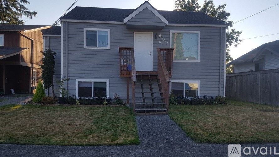 A house with a grey exterior and a white door is available for rent.