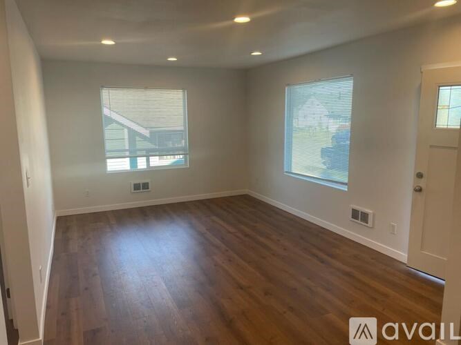 A room with wooden floors and two windows.