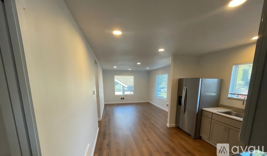 A kitchen with a refrigerator, sink, and cabinets is visible.