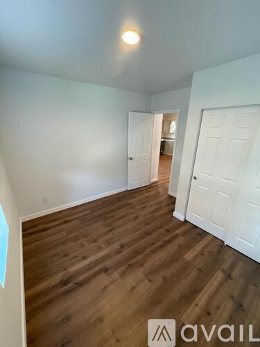 A room with wooden floors and white walls, with a door on the right.