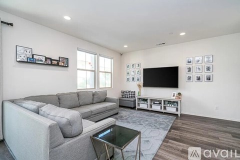 A living room with a grey couch and a television on a stand.