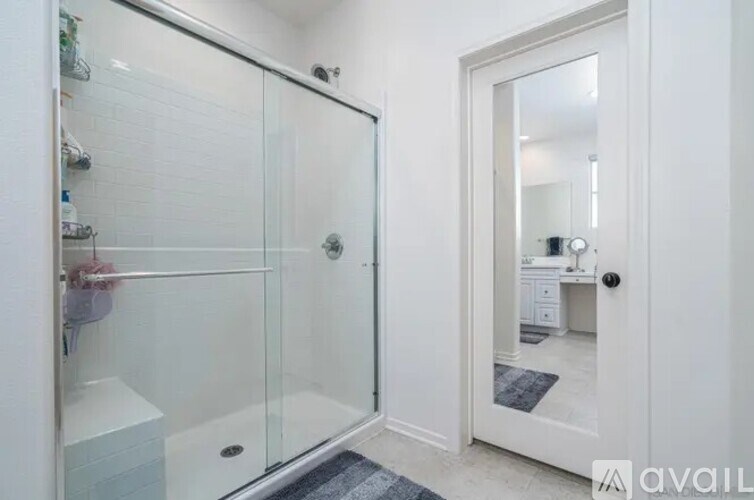 A bathroom with a glass shower door and a white door.