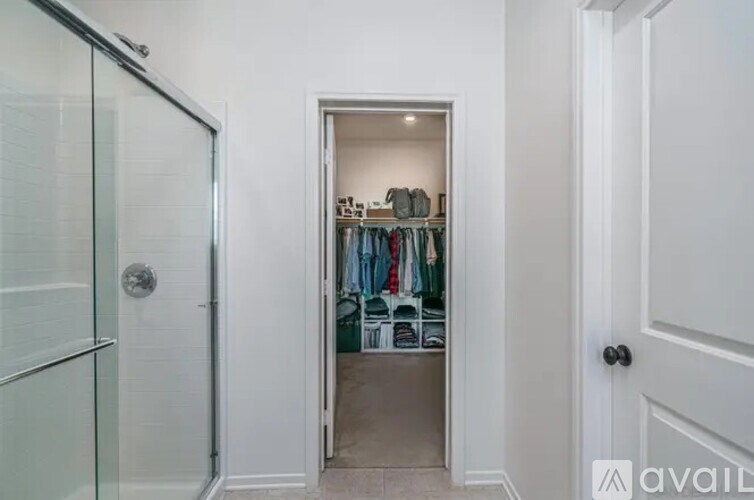 A white door is open to a closet with clothes hanging.