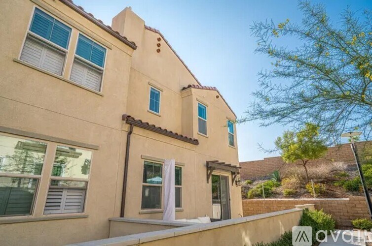 A beige house with a white awning and a tree in front.