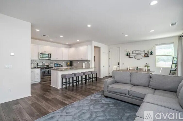 A modern kitchen with a bar and a grey sofa.