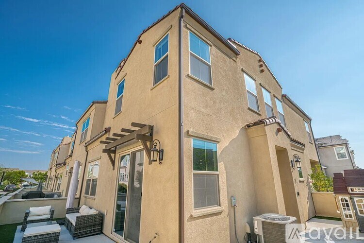 A beige stucco house with a balcony and a small garden.