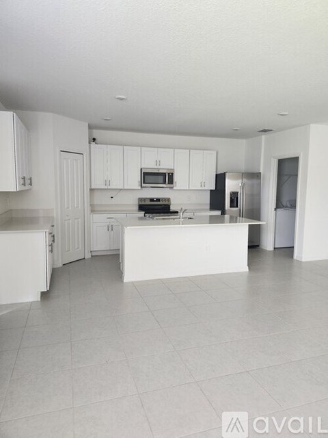 A white kitchen with a refrigerator, microwave, and oven.