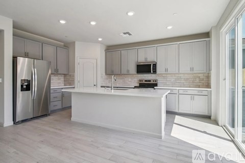 A modern kitchen with white cabinets and a stainless steel refrigerator.