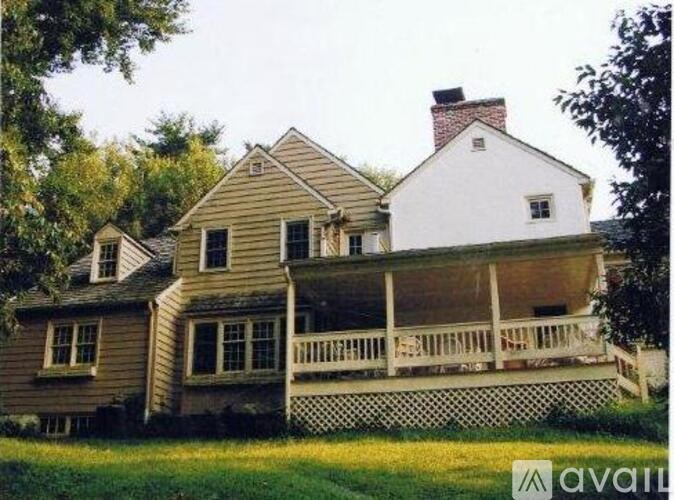 A house with a white chimney is surrounded by a white picket fence.