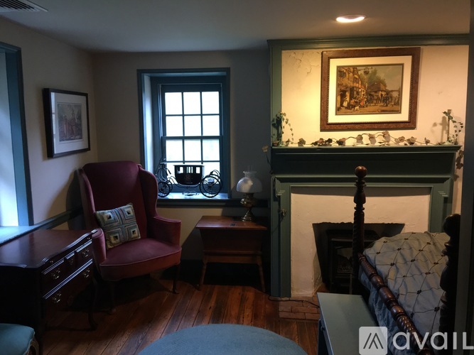 A living room with a red chair and a fireplace.