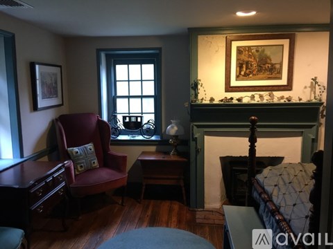 A living room with a red chair and a fireplace.