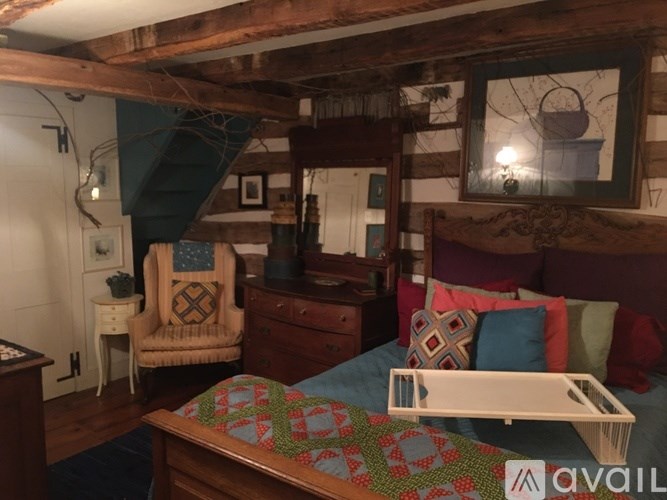 A bedroom with a bed, a chair, and a dresser.