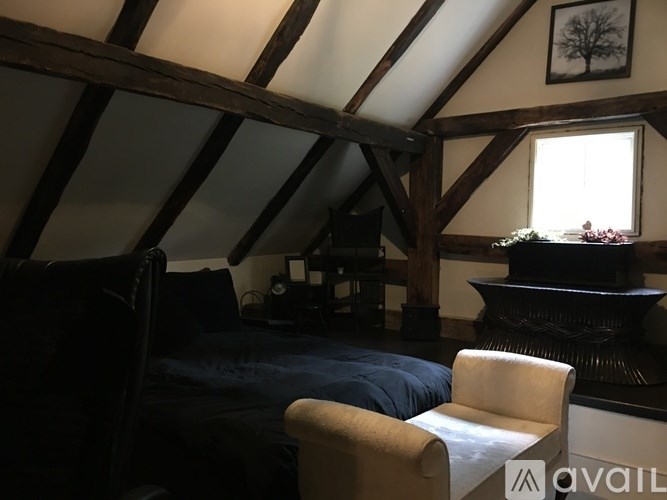 A bedroom with a bed, chair, and a fireplace.