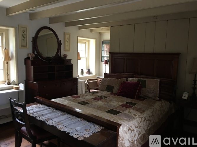 A bedroom with a large bed and a wooden dresser.