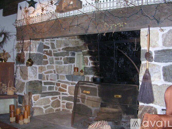 A stone fireplace with a wooden chair in front of it.