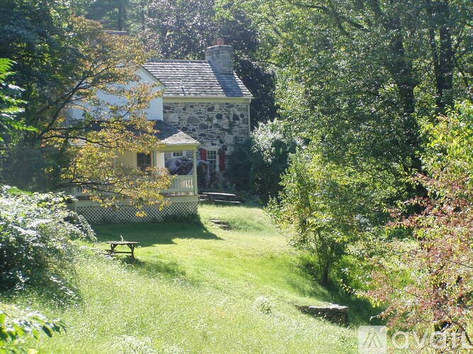 A house with a white and grey exterior is surrounded by trees and greenery.