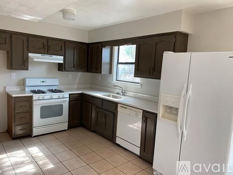 A kitchen with white appliances and brown cabinets.