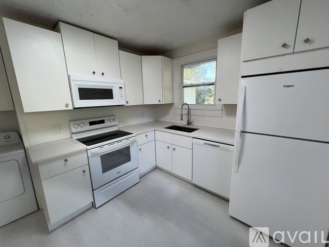 A kitchen with white appliances and cabinets.