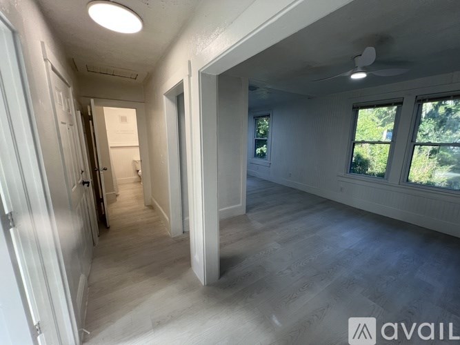 A long hallway with a door on the left and a window on the right.