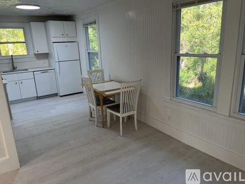 A kitchen with white appliances and a dining table with chairs.