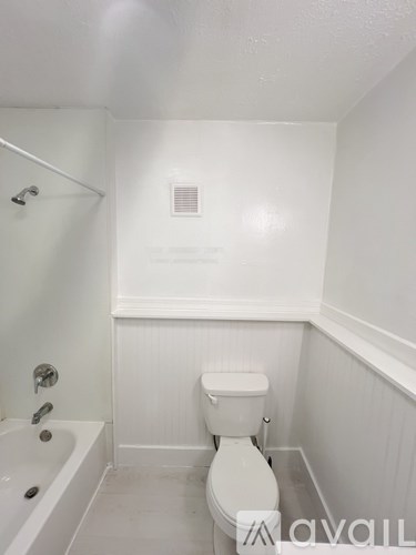A kitchen with white cabinets and appliances, a window with a view of greenery outside, and a wooden chair.