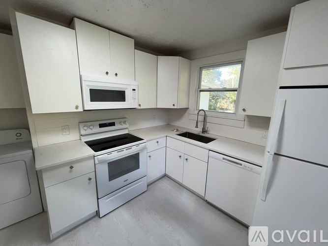 A white kitchen with a microwave, oven, sink, and refrigerator.
