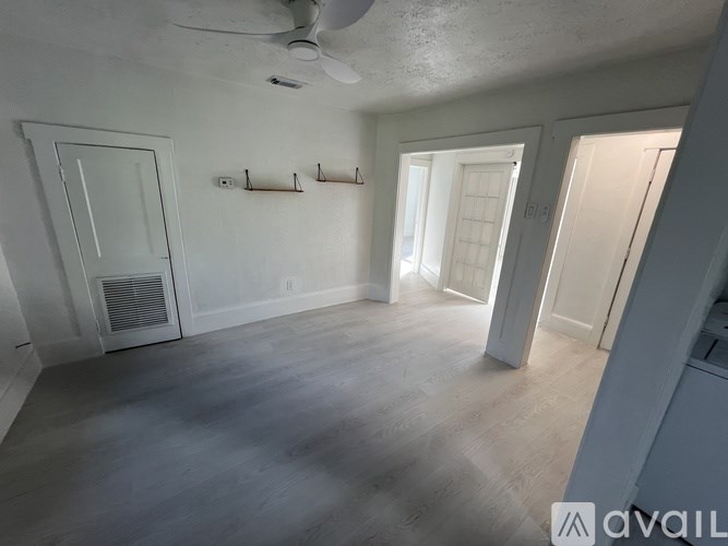 A spacious room with a ceiling fan and a row of hooks on the wall.