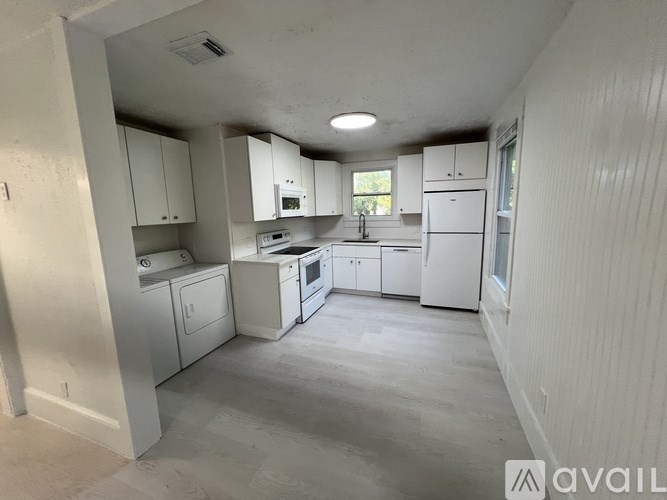 A kitchen with white appliances and cabinets is available for rent.
