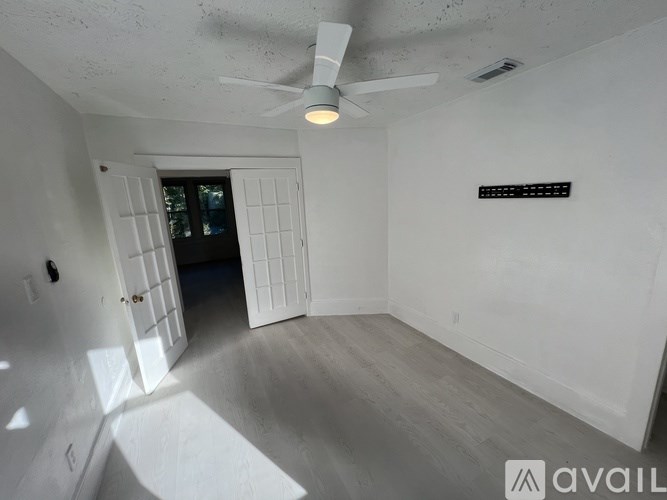 A room with a ceiling fan and a door leading to another room.