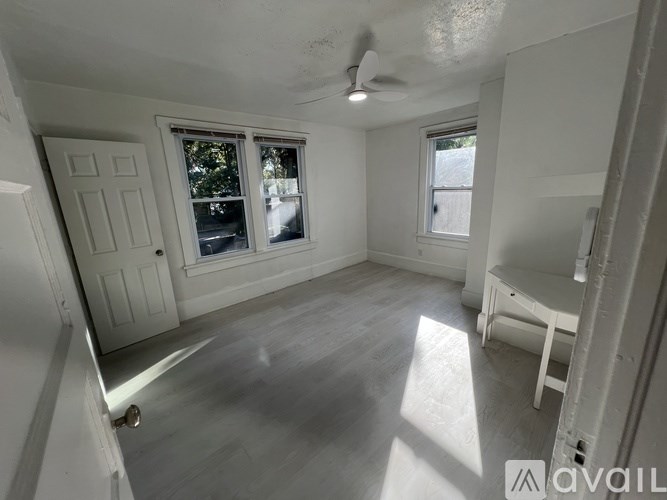 A room with a ceiling fan and two windows.
