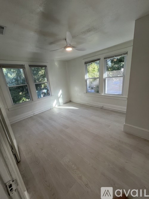A room with a ceiling fan and three windows.