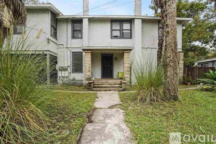 A house with a front yard and a concrete path leading to the front door.