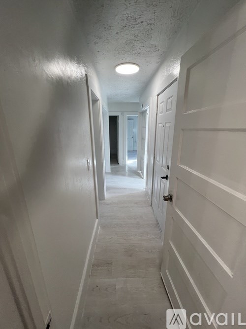 A long hallway with white walls and doors on the side.