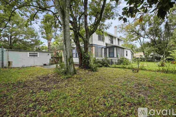 A house with a large yard and trees in front.