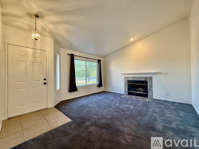 A room with a fireplace and a window with curtains.