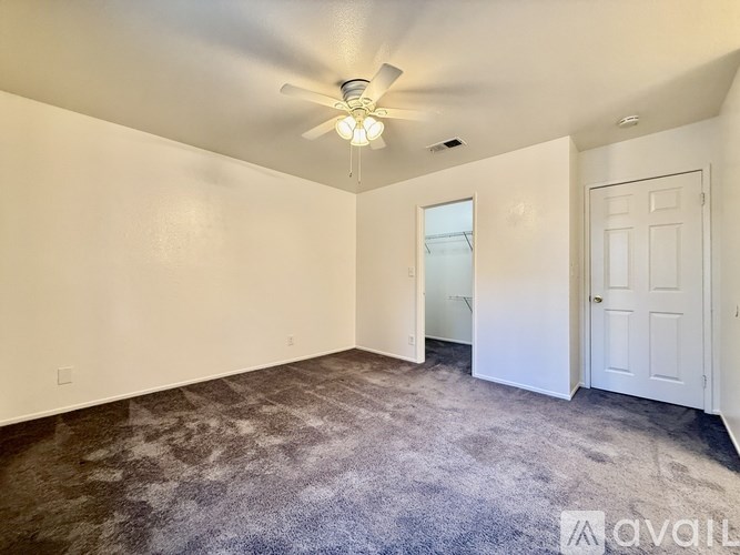 A room with a carpeted floor and a ceiling fan.