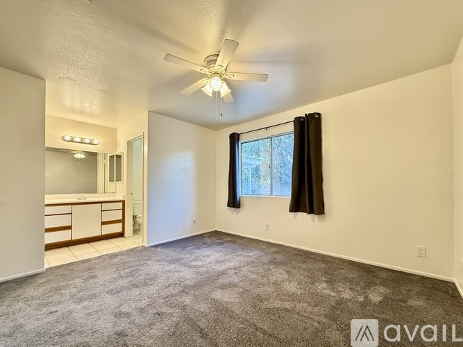 A spacious room with a ceiling fan and carpeted floor.