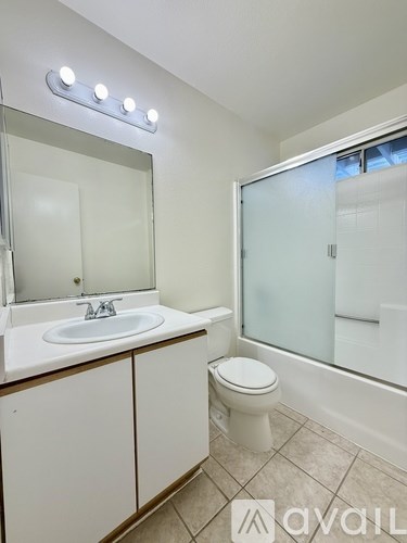 A bathroom with a sink, toilet, mirror, and shower.